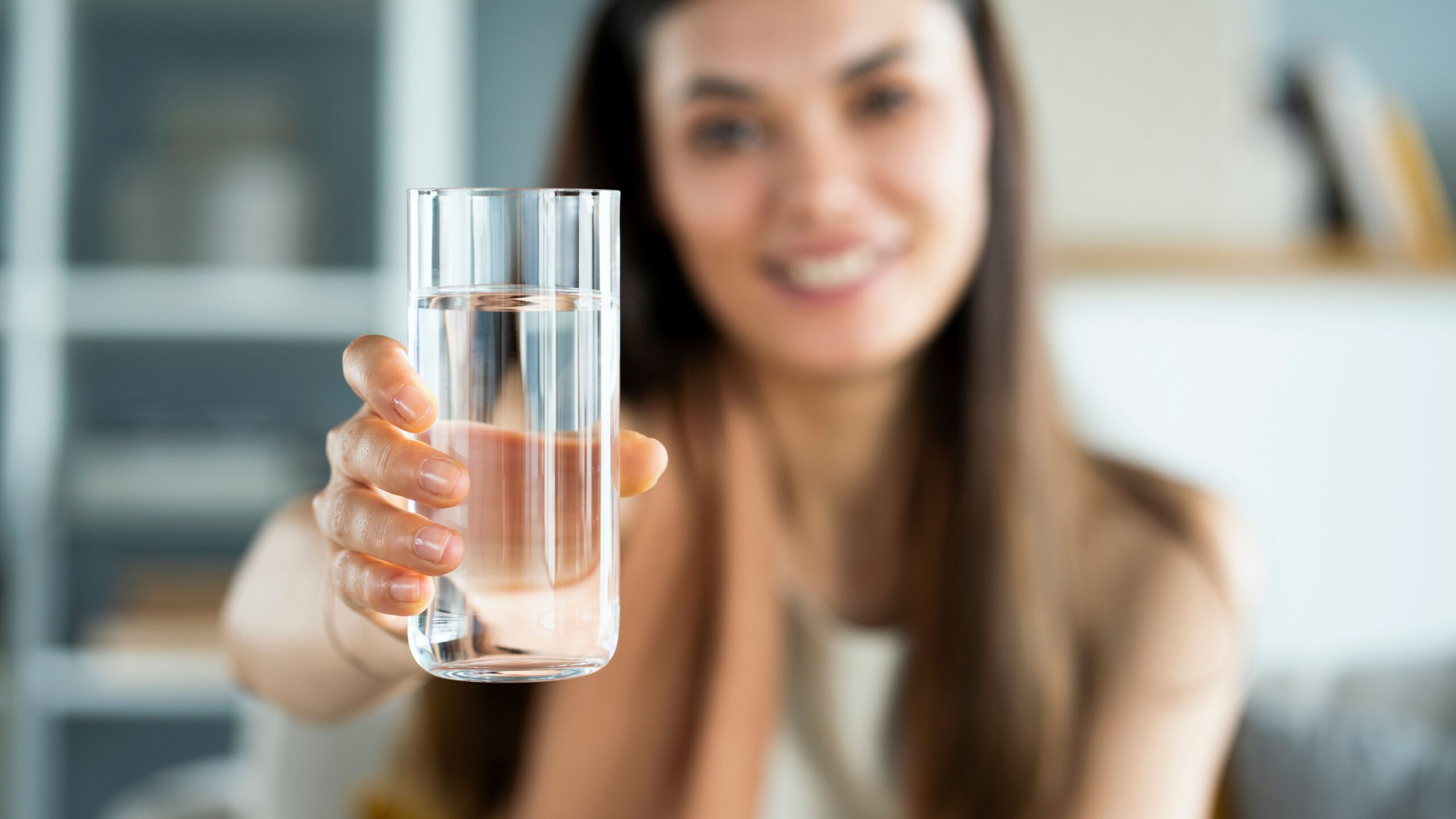 Frau hält ein Glas mit klarem Wasser